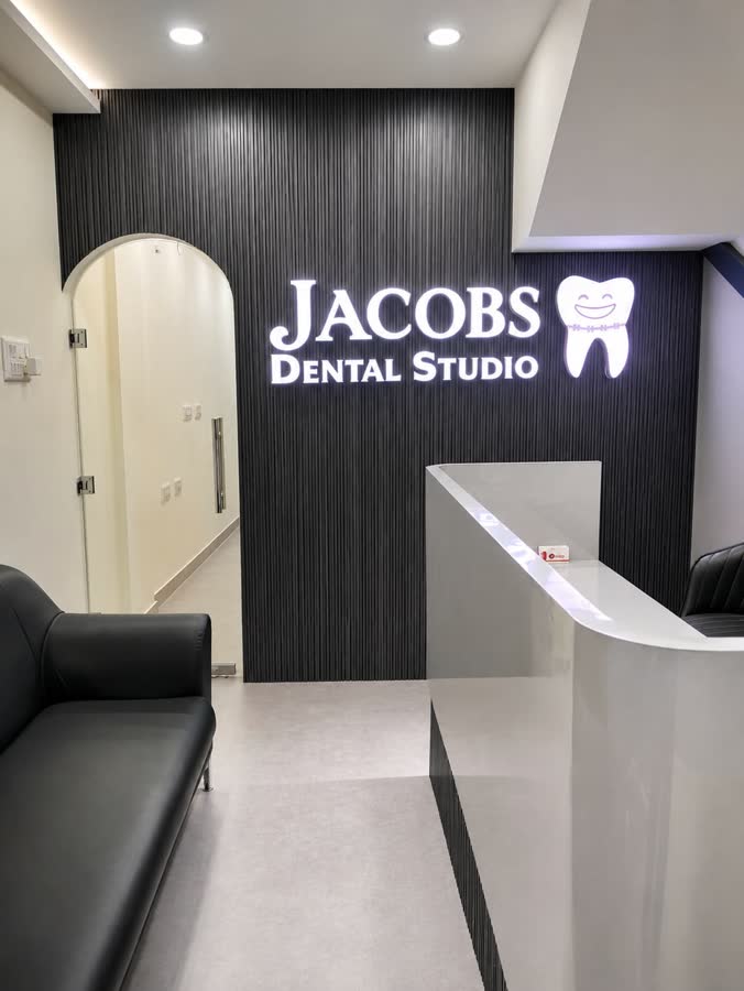 The front desk, with the JACOBS Dental Studio sign lit on the fluted wall behind it
